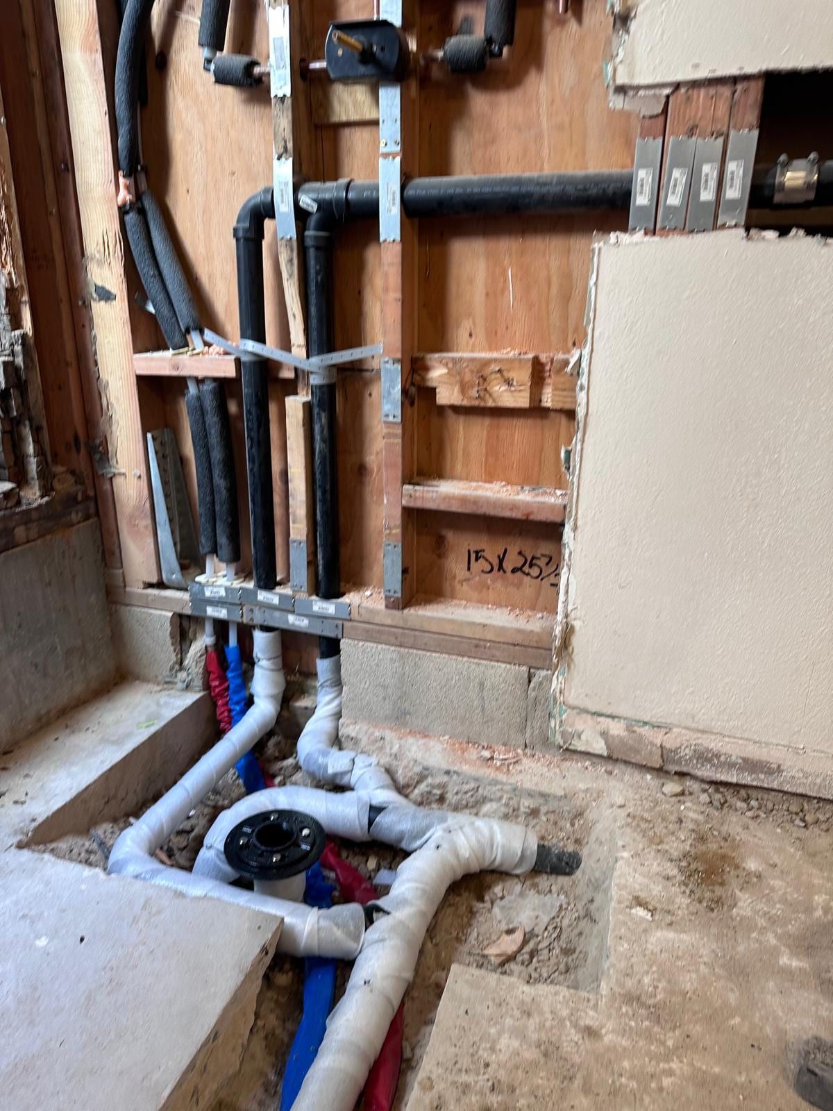 Bathroom rough-in on one of our jobs: new PEX supply lines and a closet flange set into the slab, cast-iron stack behind
